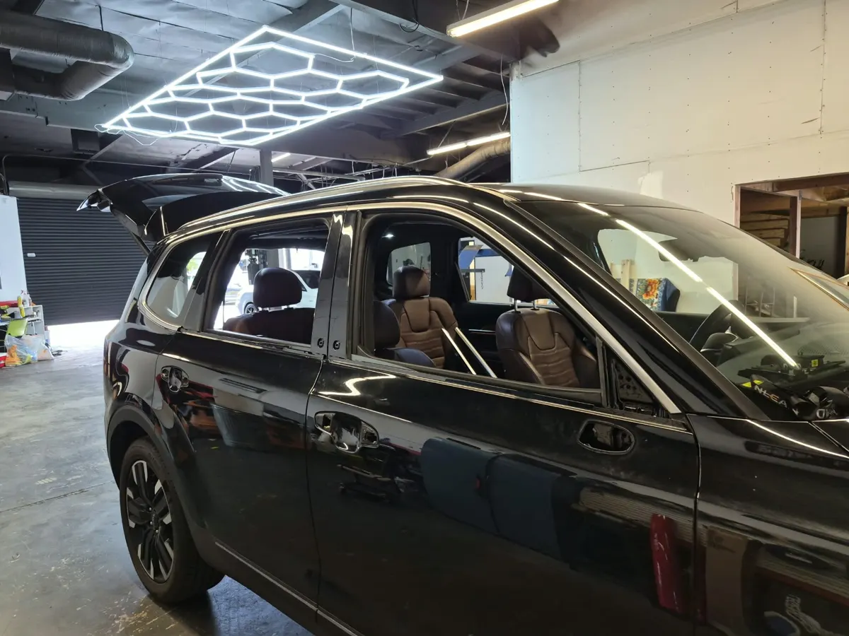 Black vehicle inside a shop with door-handle and mirror areas exposed