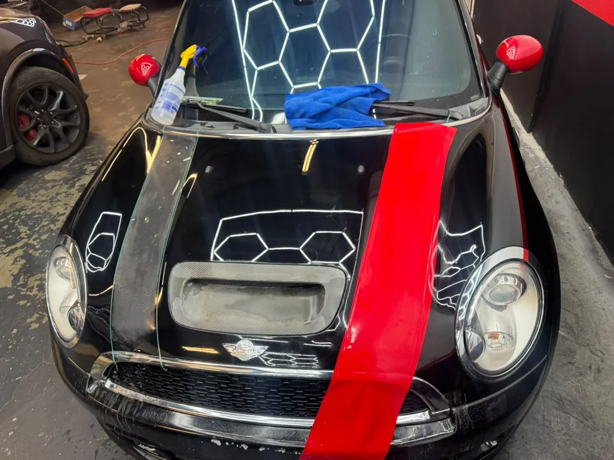 Red wrap material on a black hood beside a blue towel and spray bottle