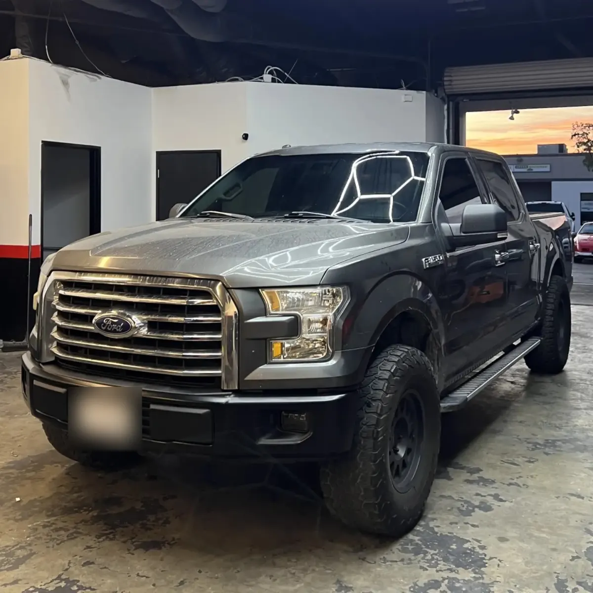 Ford F-150 pickup at the Enhanced Automotive shop with a satin black wrap on the front bumper