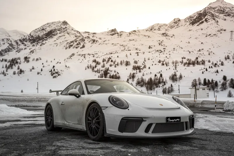 White sports car displayed before snowy mountains