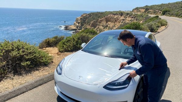 Professional applying Tesla PPF paint protection film in San Diego coastal setting